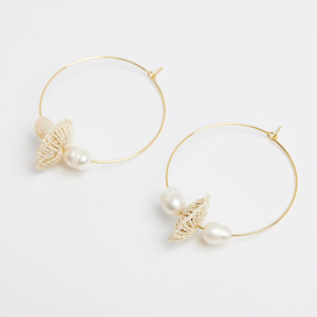Side angle of gold hoops with pearl and natural fibre discs