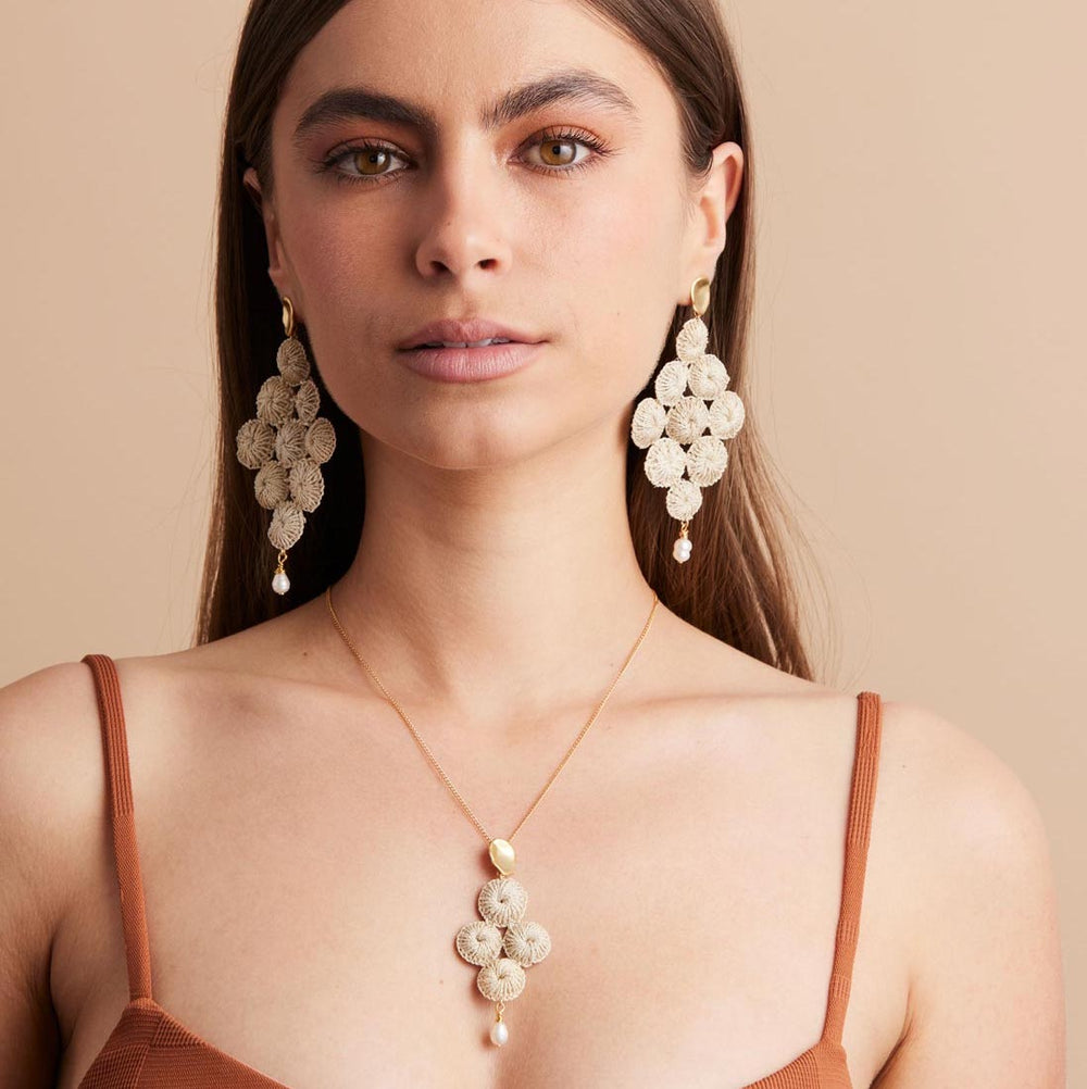Gold and pearl with woven natural fibre statement Malalo Chandelier earrings on a model