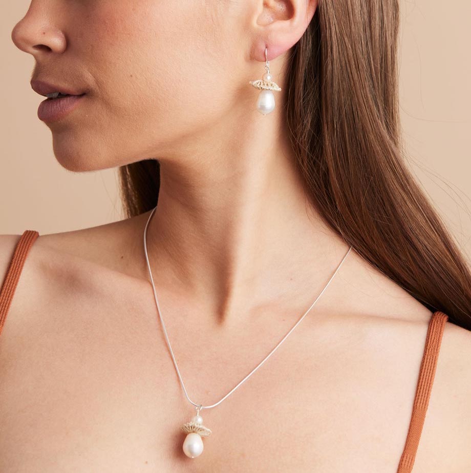 Model’s profile wearing silver pearl drop earrings with matching necklace
