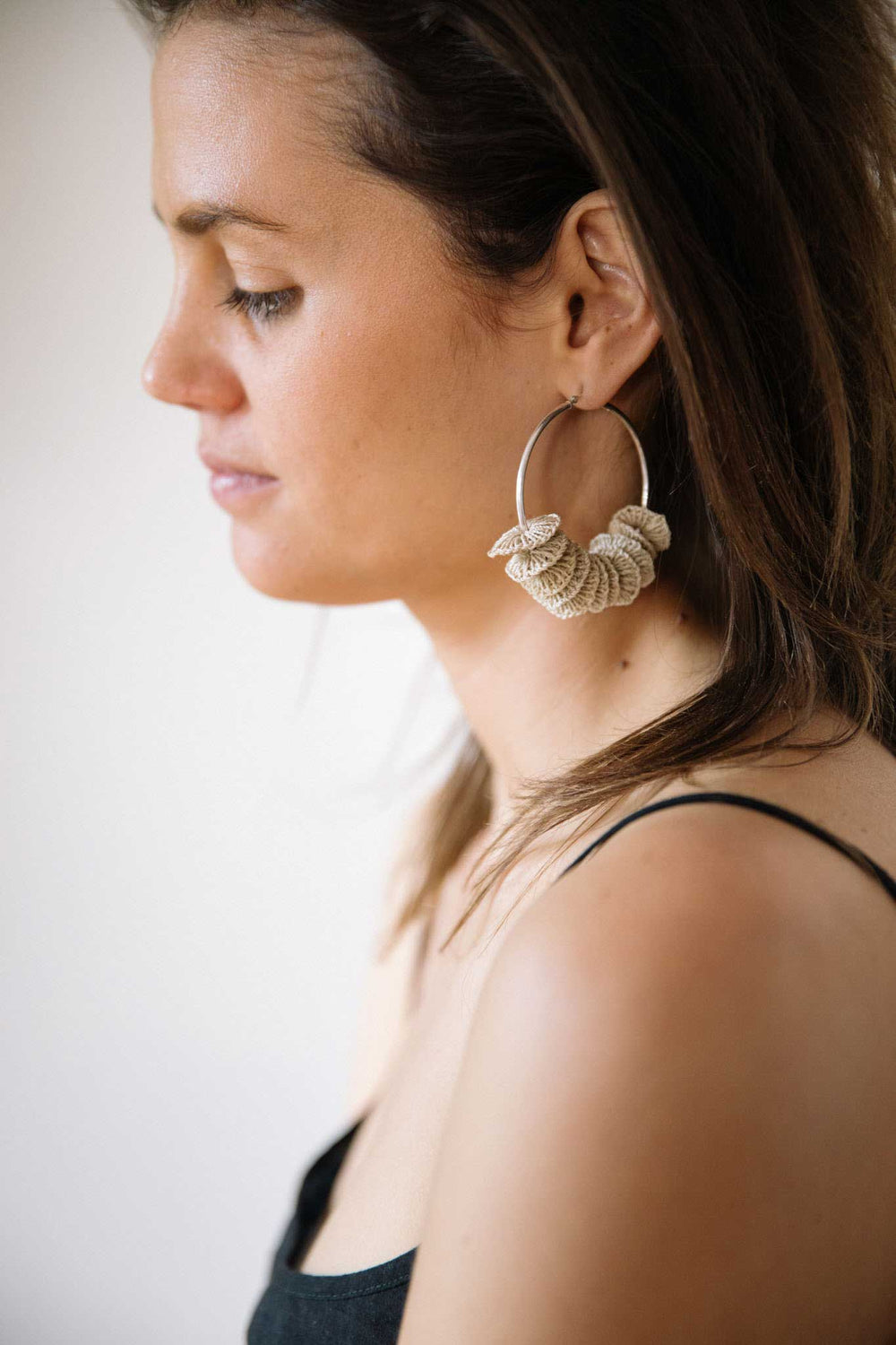 Model wearing Bilum and Bilas sterling silver endless hoop earrings with textile bead stacks